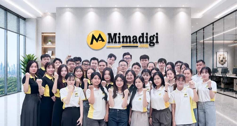 Đội ngũ MIMA nắm tay tạo dáng trước bảng hiệu Mimadigi ở sảnh văn phòng