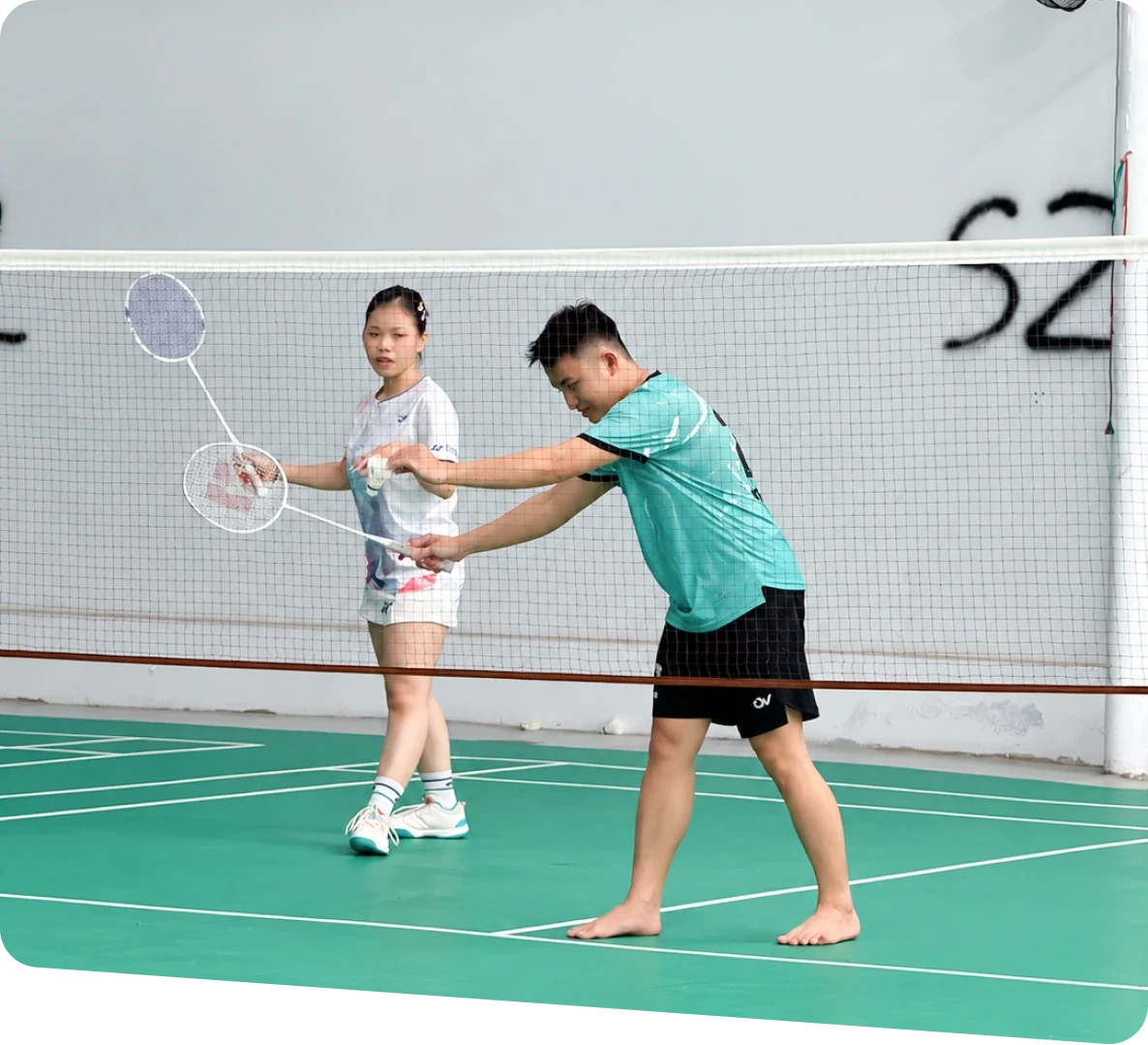 A MIMA team member showing a colleague how to hold a badminton racket