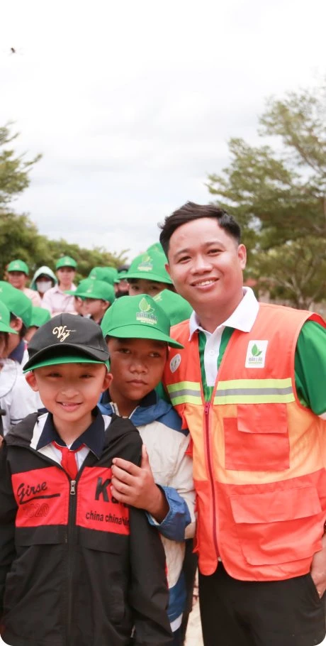 A MIMA team member in a volunteer vest posing with children